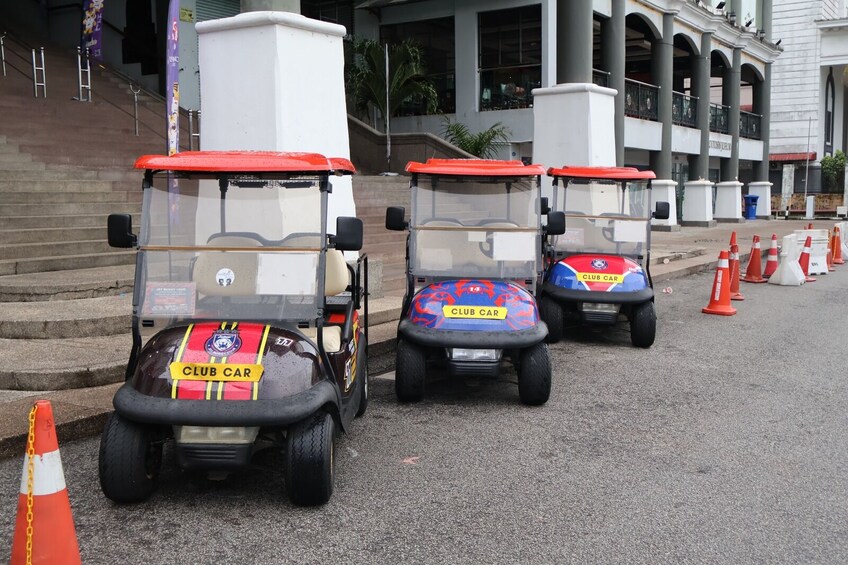 Three golf carts parked on a street with orange traffic cones. 5