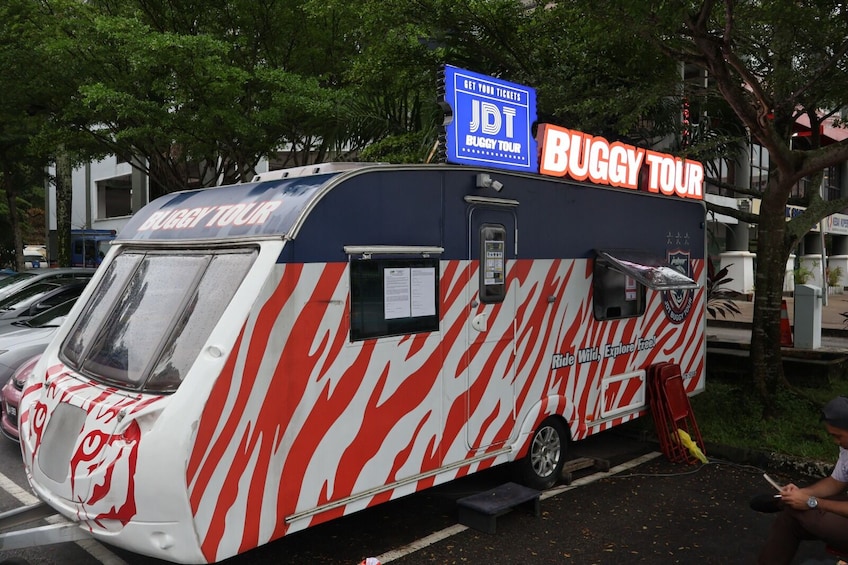 A Buggy Tour vehicle with a red and white zebra stripe design, parked on a street. 3