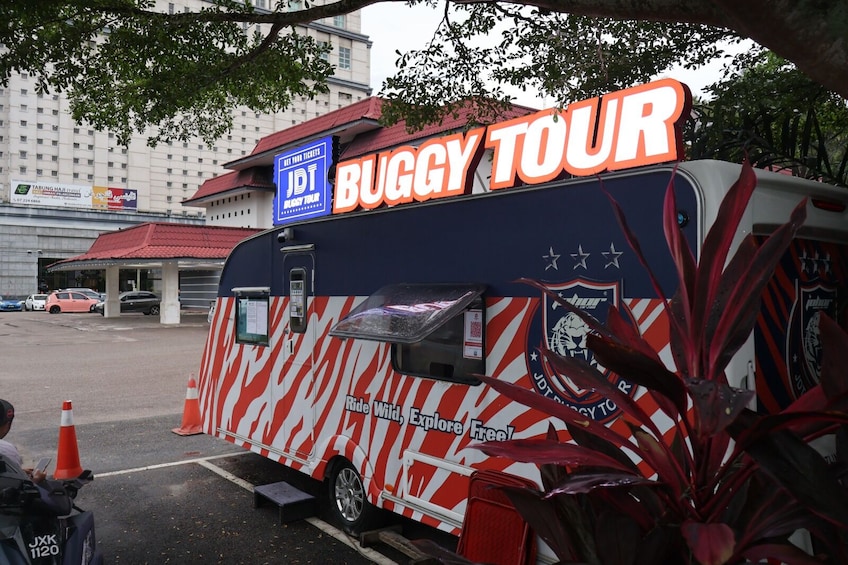 A bus with 'BUGGY TOUR' signage parked in a lot. 1