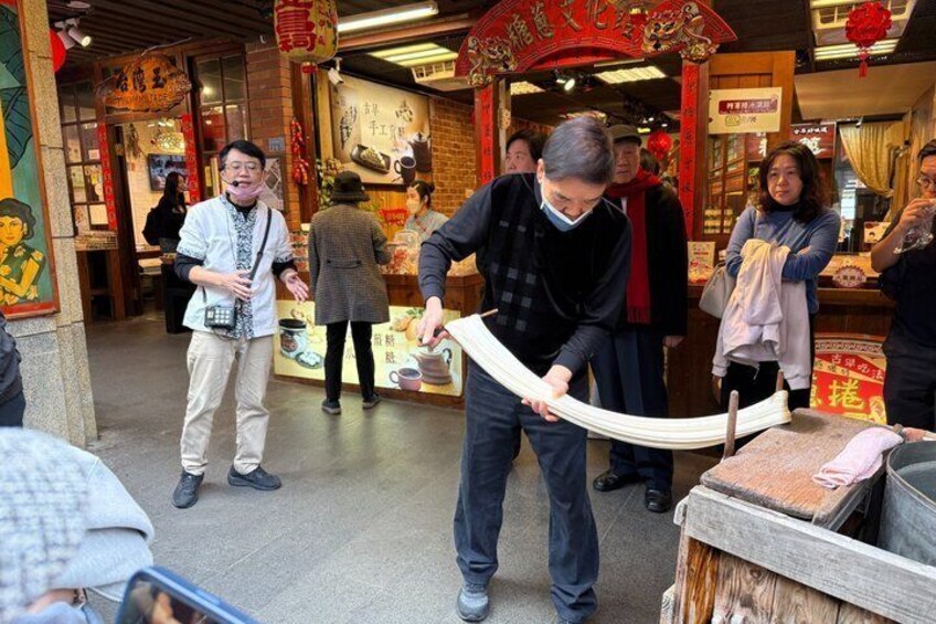 A person demonstrating the use of a traditional tool in a market setting. 4