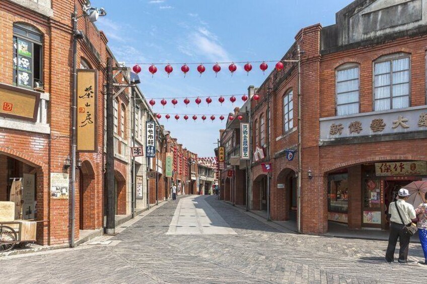 A street lined with brick buildings, red lanterns, and signs in a foreign script. 5