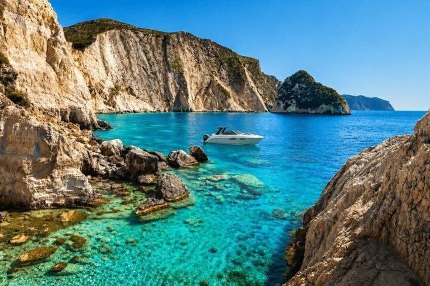 A coastal landscape with clear turquoise waters, rocky cliffs, and a small boat. 1