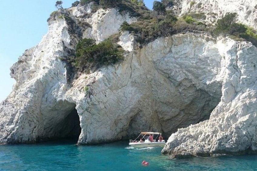 A rocky coastal landscape with a boat near a cave entrance. 2