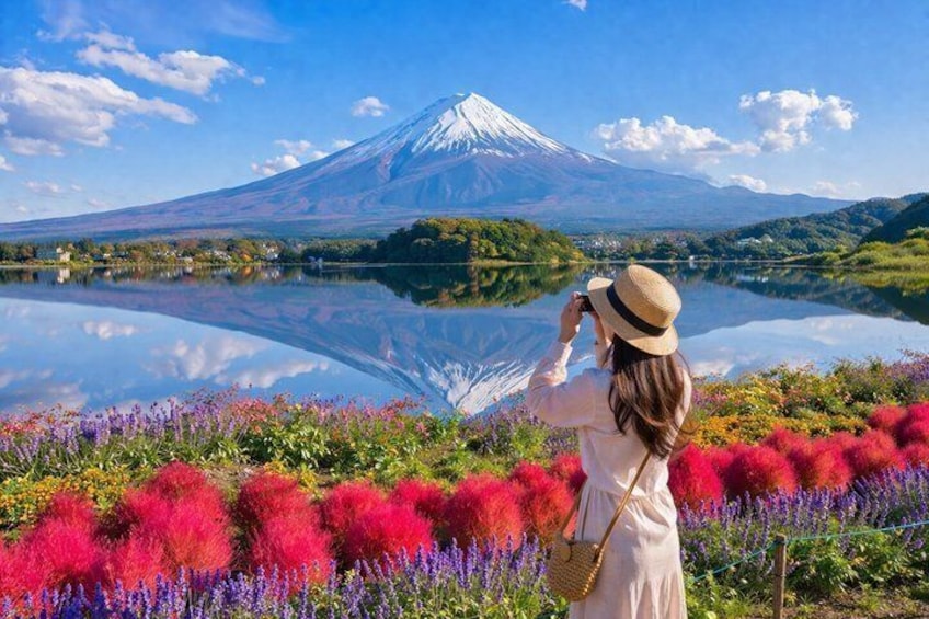 A woman taking a photo of Mount Fuji reflected in a lake, surrounded by colorful flowers. 4