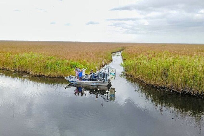 A boat on a calm waterway surrounded by tall grasses. 2
