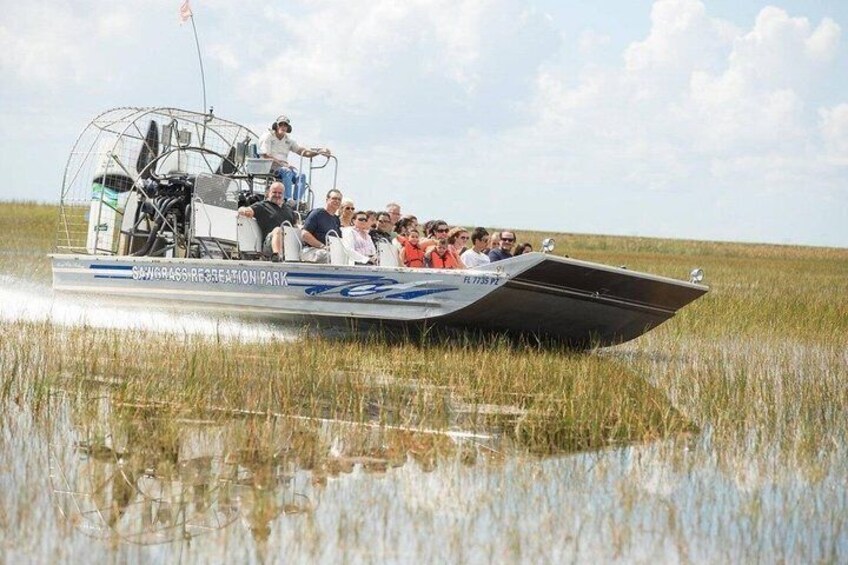 A boat with passengers on a marshy landscape. 1