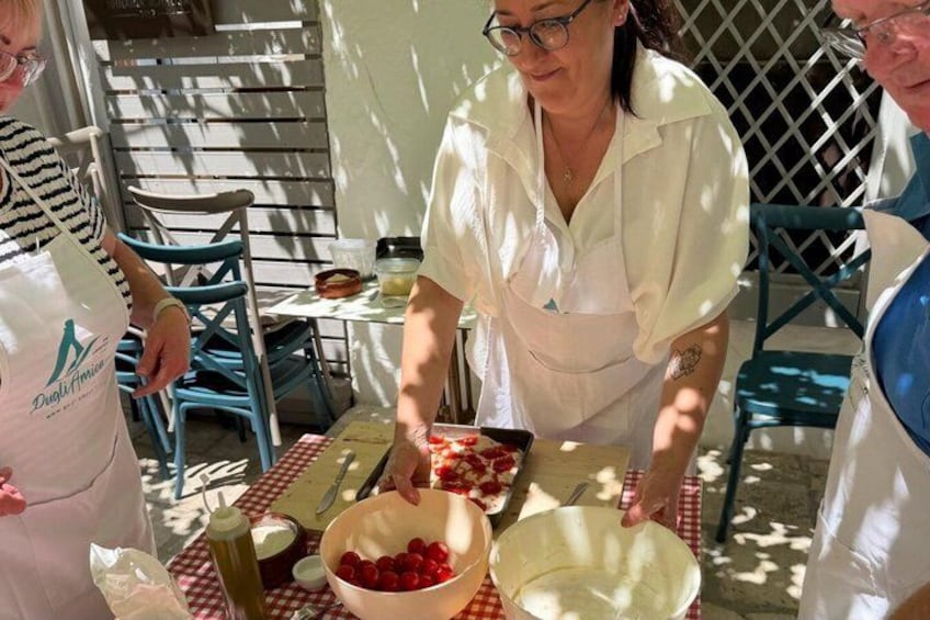People preparing food outdoors with a table, chairs, and a fence in the background. 3