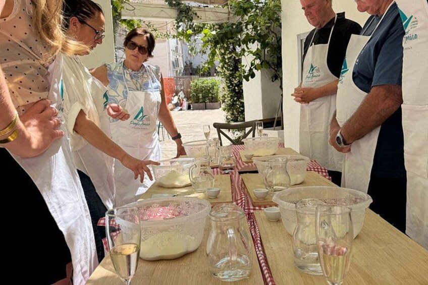 People engaged in a cooking activity outdoors, with cooking utensils and ingredients on a table. 3
