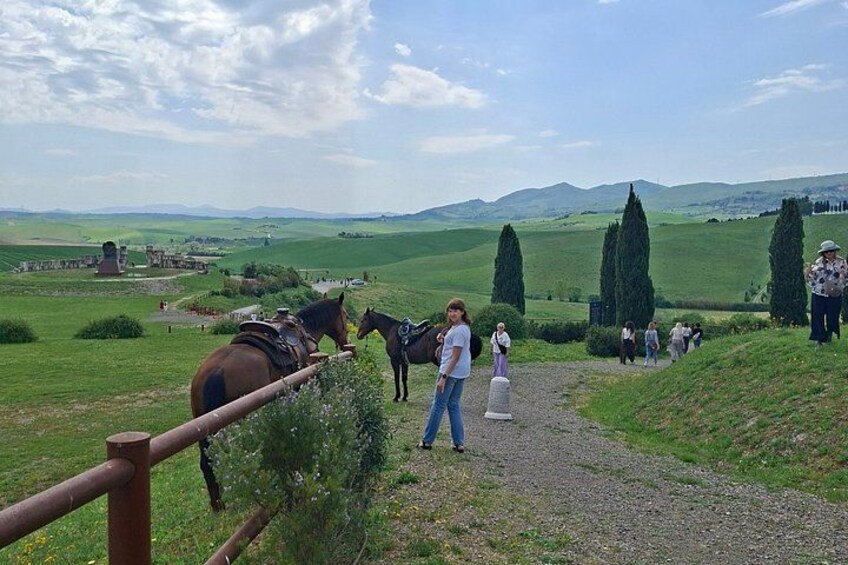 A rural landscape with horses, a gravel path, and people walking. 2