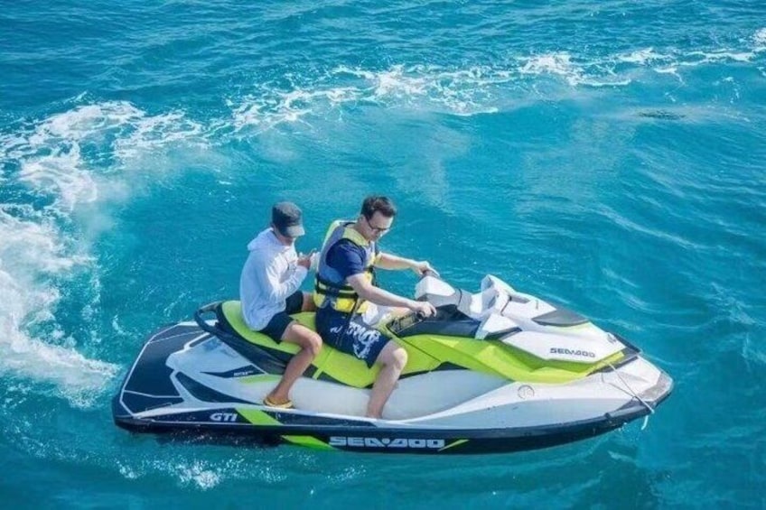 Two people on a jet ski in blue and green water. 1