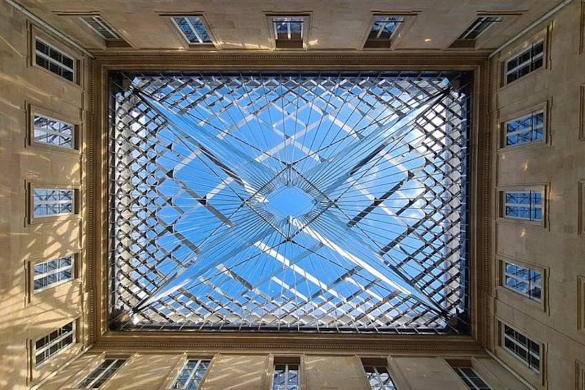 A large glass skylight with a geometric pattern, surrounded by a stone structure. 5