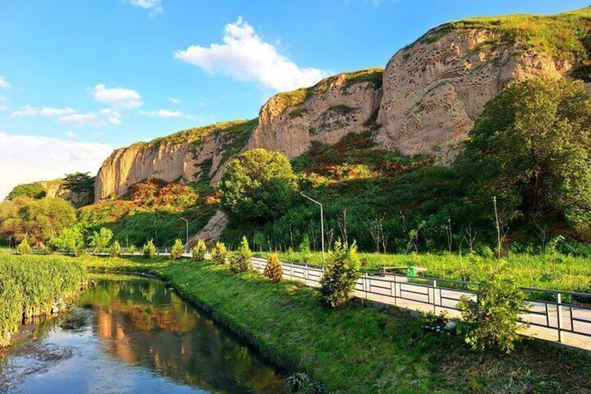 A river, greenery, a bridge, and a rocky cliff. 5