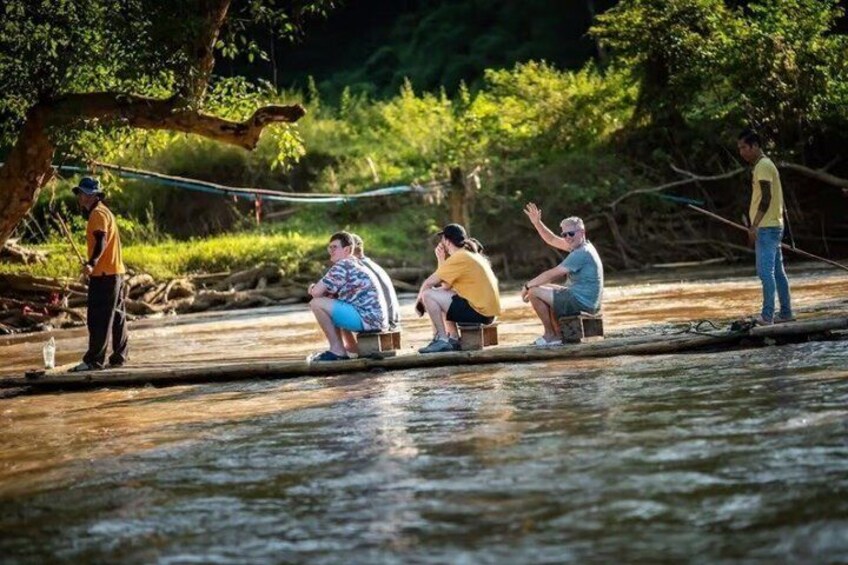 People sitting on wooden platforms by a river, fishing. 3