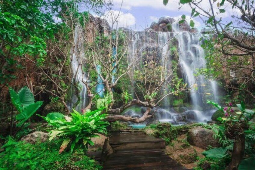 A waterfall cascading over rocks surrounded by lush greenery. 1