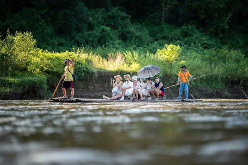 People on a river, some standing and others sitting, with a guide leading them. 3