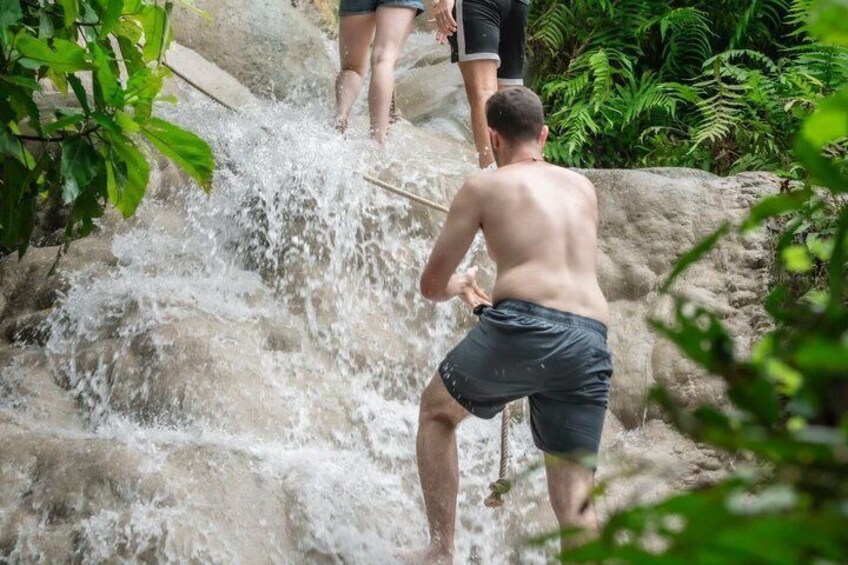 A man in shorts playing with water at a waterfall. 5