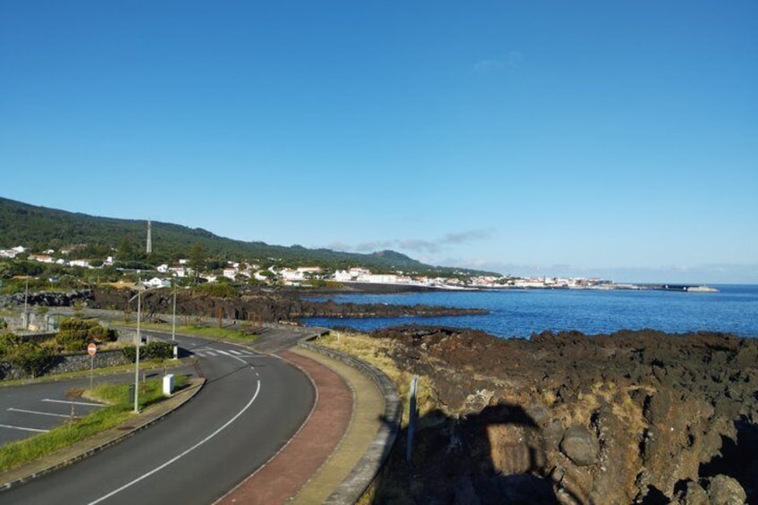 A coastal road curving alongside a rocky shoreline with a clear blue sky. 5