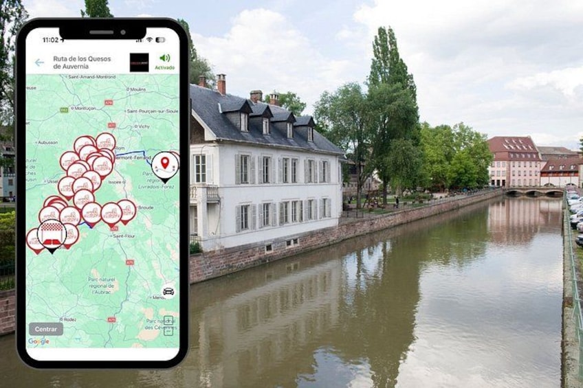 A smartphone displaying a map with marked locations, a river, and buildings in the background. 1