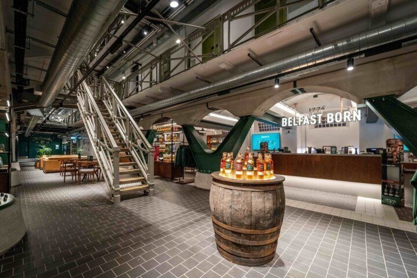 A modern interior with a staircase, a wooden barrel, and a counter labeled 'BELFAST BORN' with a vintage vibe. 5