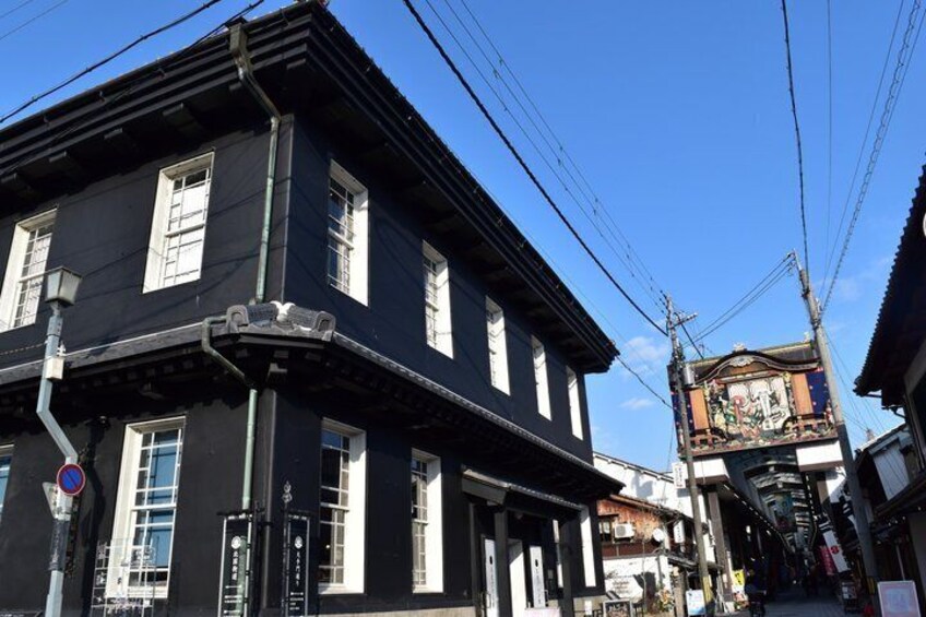 A traditional Japanese building with a black facade and white window frames, a clear blue sky, and power lines overhead. 5