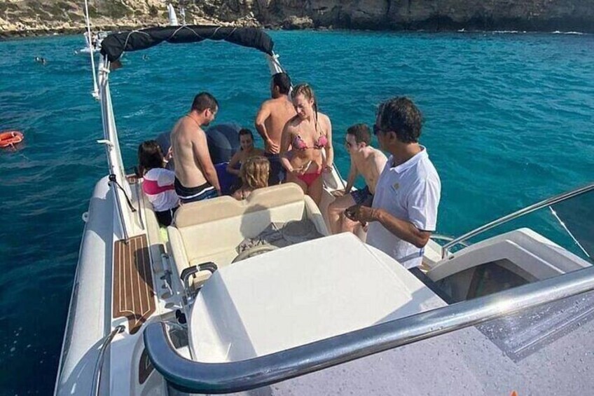 A group of people on a boat in a body of water with a rocky coastline in the background. 1