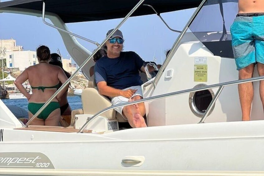 A boat with people on board, a clear sky, and buildings in the background. 5