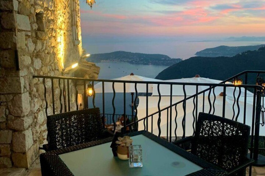 A terrace with stone walls, a table, chairs, and a view of a coastal landscape. 2