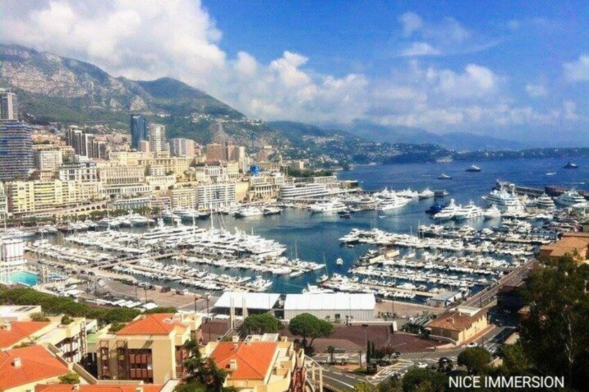 A marina with numerous boats, a cityscape with buildings, and mountains in the background. 5