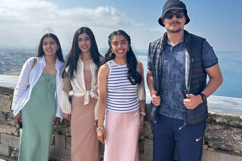 A group of people standing on a stone wall overlooking a coastal landscape. 5