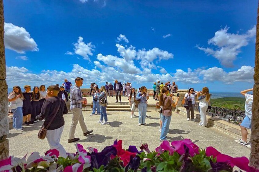 A group of people standing on a stone platform overlooking a landscape. 2