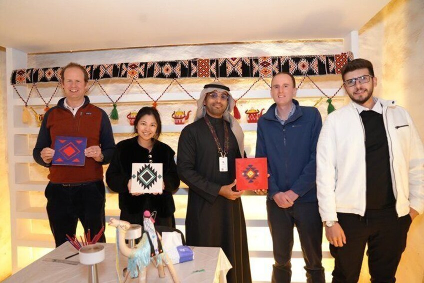 A group of people standing in a room with a patterned wall and a table with various items. 2