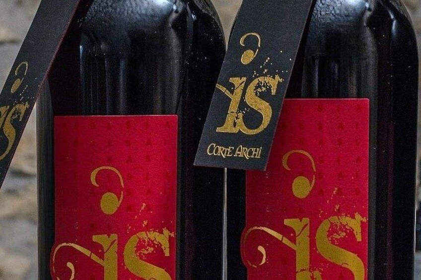 Three wine bottles with red labels and gold text, including 'Corse Archi'. 2