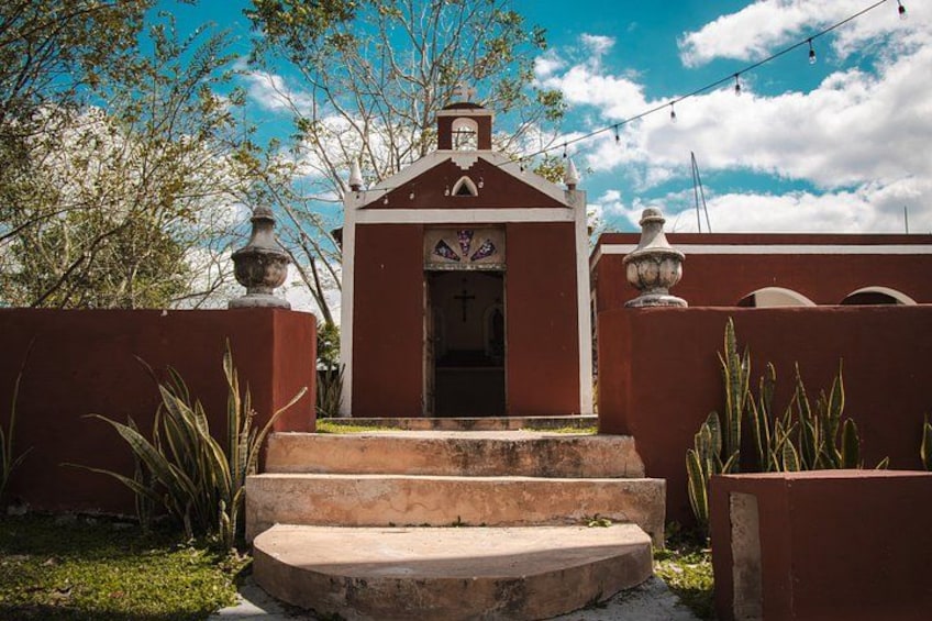 A small building with a red facade, a white door, and a staircase leading up to it. 4
