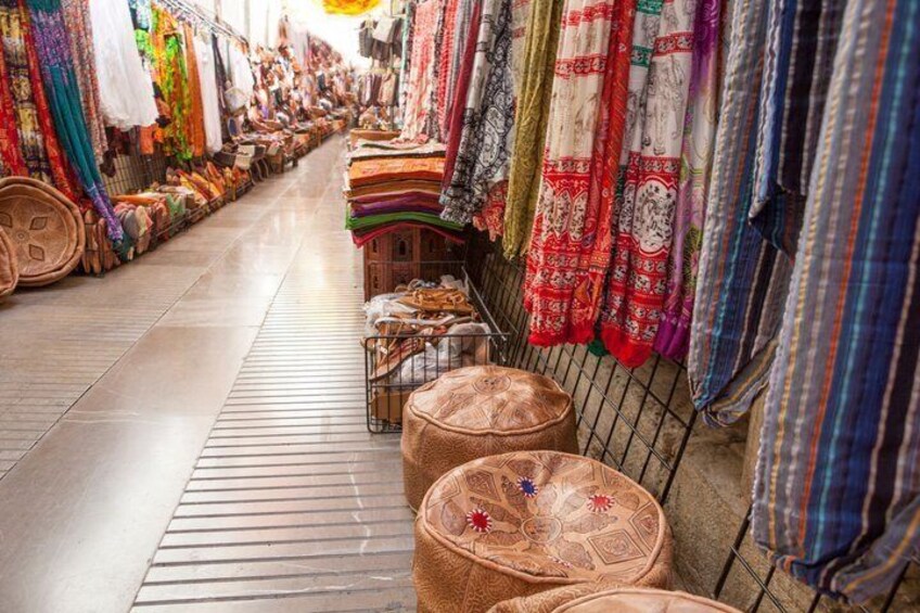 A market aisle with colorful textiles and patterned rugs. 4