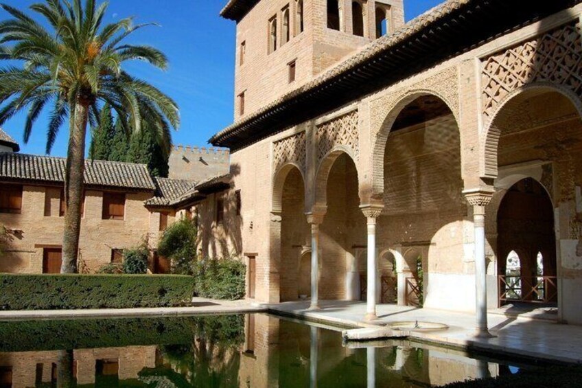 A courtyard with arches, a pool, and palm trees. 1