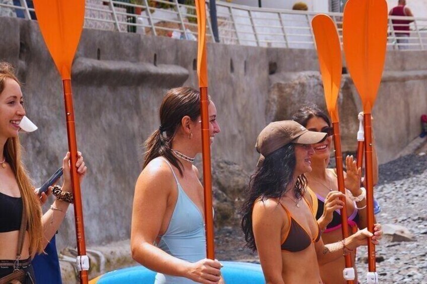 A group of people holding paddles, standing by a body of water. 5