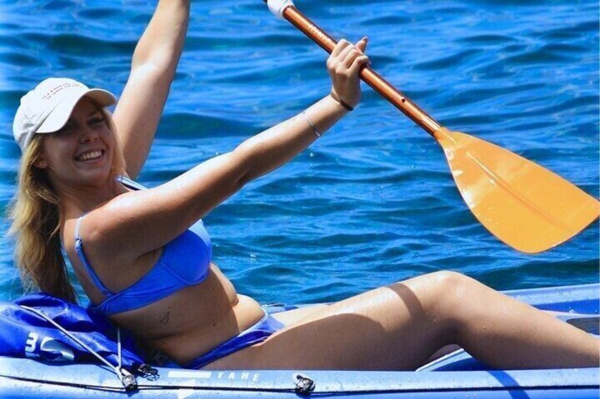 A person in a blue swimsuit paddling a kayak on a body of water. 1