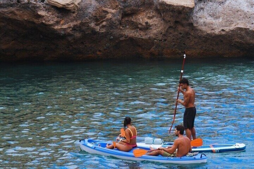 A person paddling a canoe in a calm river with rocky banks. 2