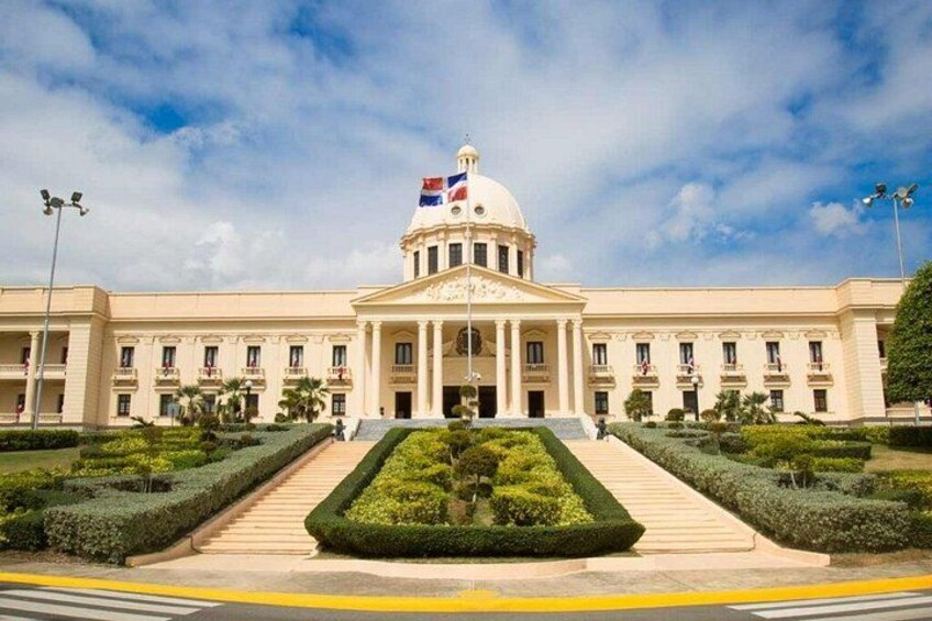 A large, classical building with a central dome, flag, and formal entrance. 2