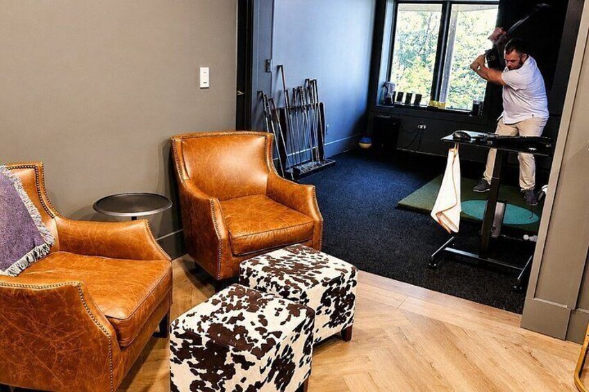 A room with leather chairs, a patterned ottoman, and exercise equipment. 4