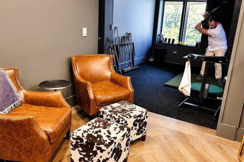 A room with leather chairs, a patterned ottoman, and exercise equipment. 4
