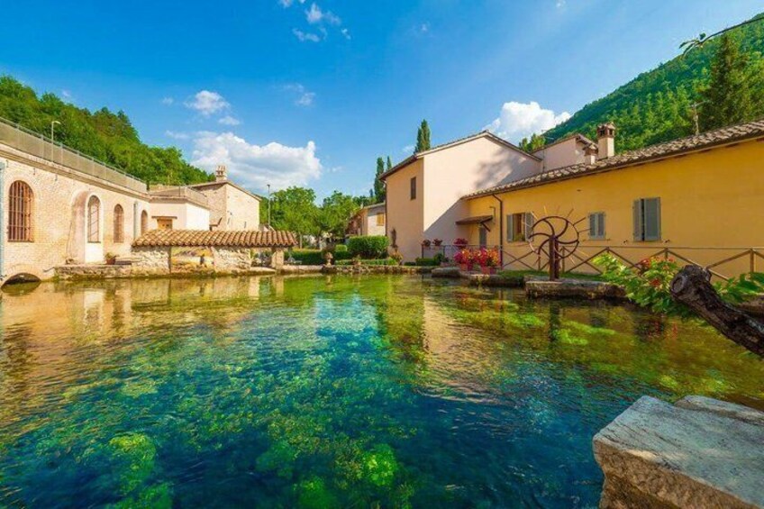 A clear water body reflecting buildings, surrounded by greenery and a clear sky. 1