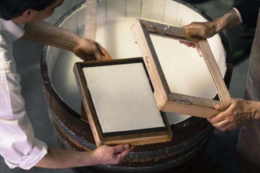 Two individuals holding a wooden picture frame with a white canvas. 3