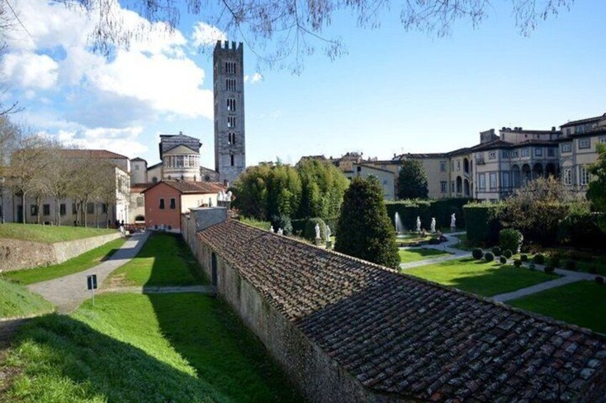 A historic town with a prominent tower, a well-maintained garden, and a stone wall. 2