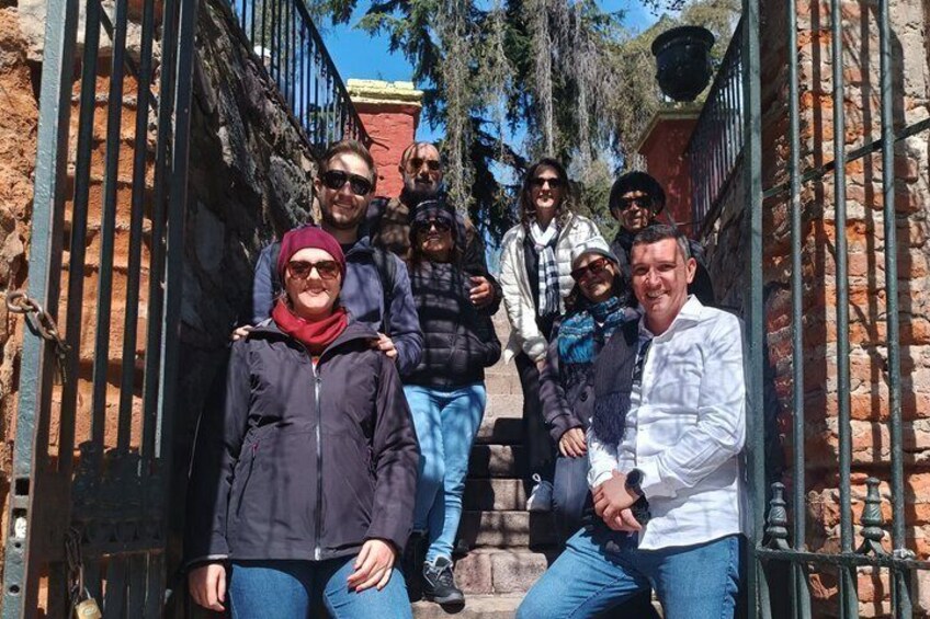 A group of people standing in a narrow alleyway with stone walls and metal gates. 4