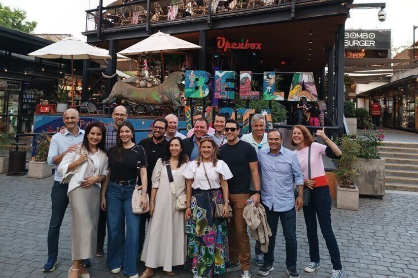 A group of people posing in front of a colorful storefront with a sign that reads 'BELA.' 5