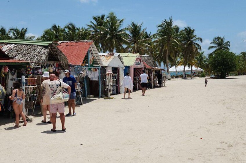 A beach with palm trees, a sandy shore, and small shops. 4