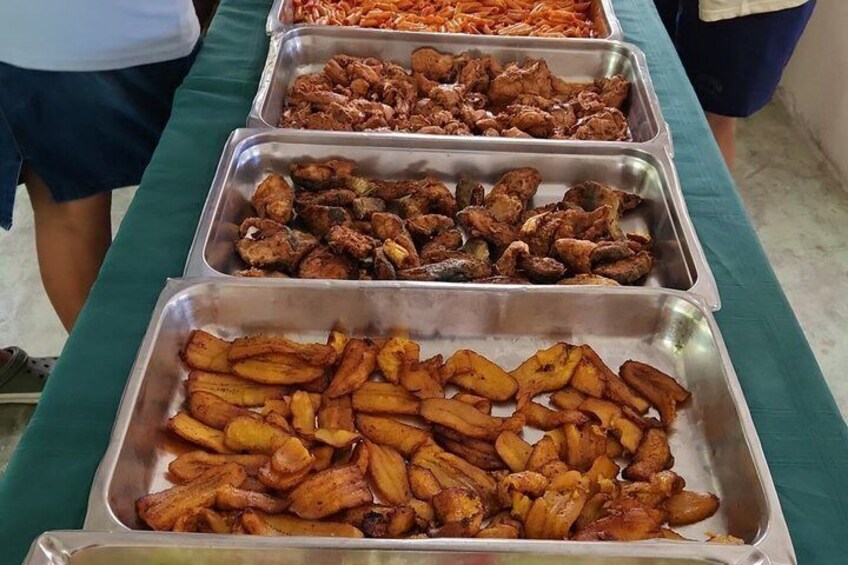 A buffet table with various food items including fried chicken, wings, and plantains. 2