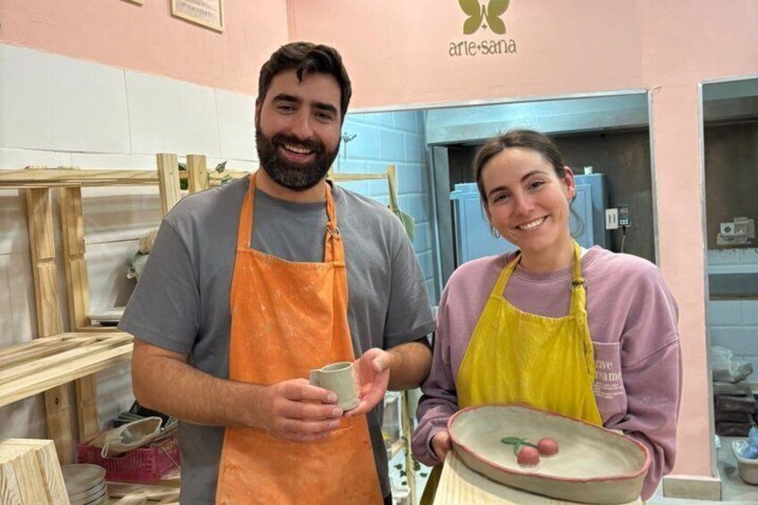 Two people in a workshop with wooden planks and a pottery wheel. 5