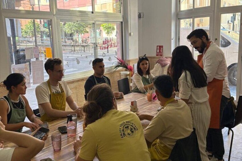 A group of people seated around a table in a cafe with large windows. 2